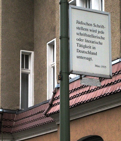 A street sign with german writing on it explaining that Jewish authors are no longer allowed to write as of March 1935.
