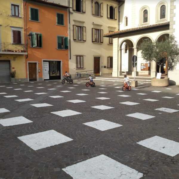 An empty plaza with white squares painted on the ground, arranged in a grid distanced apart.