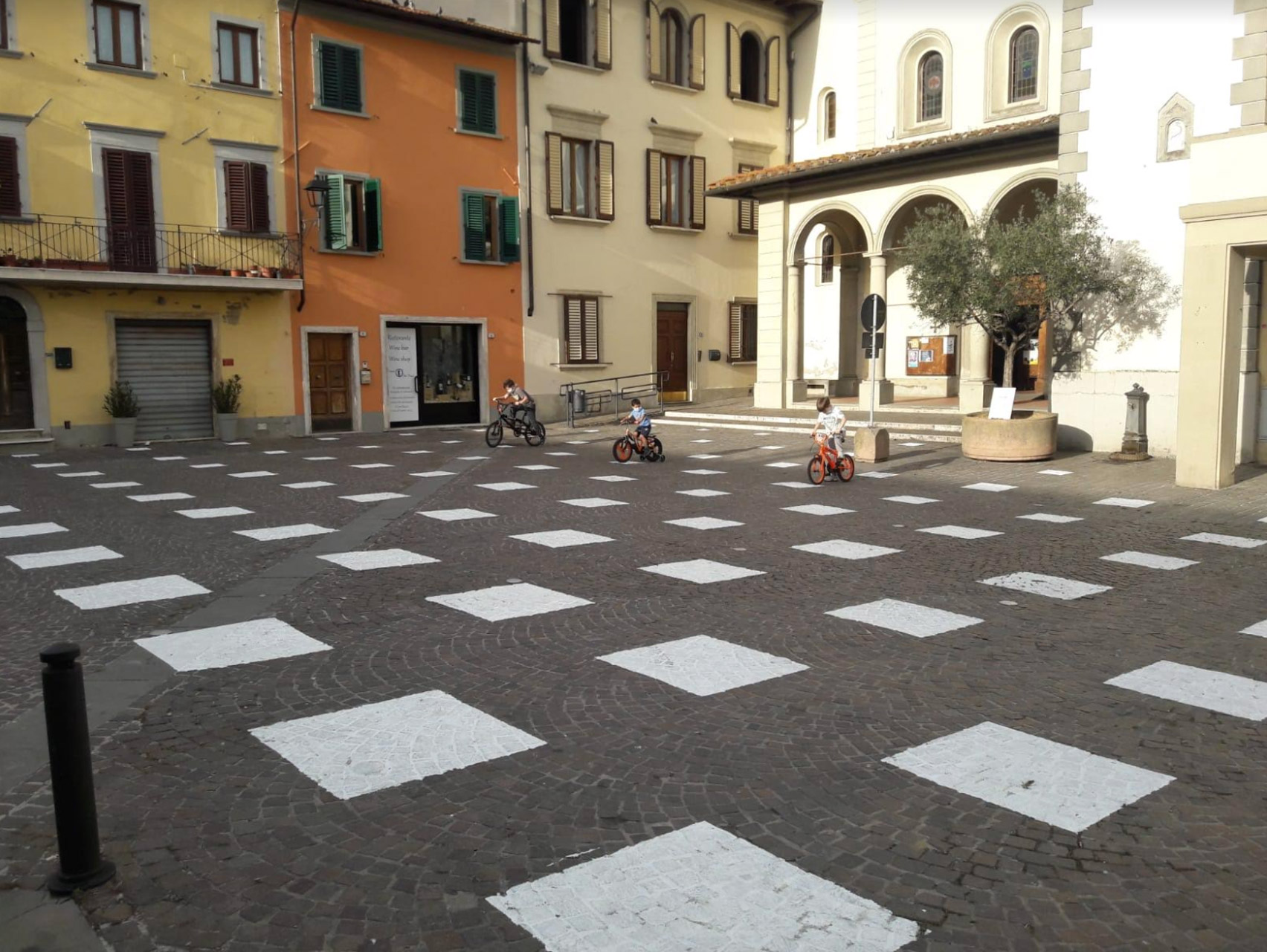 An empty plaza with white squares painted on the ground, arranged in a grid distanced apart.